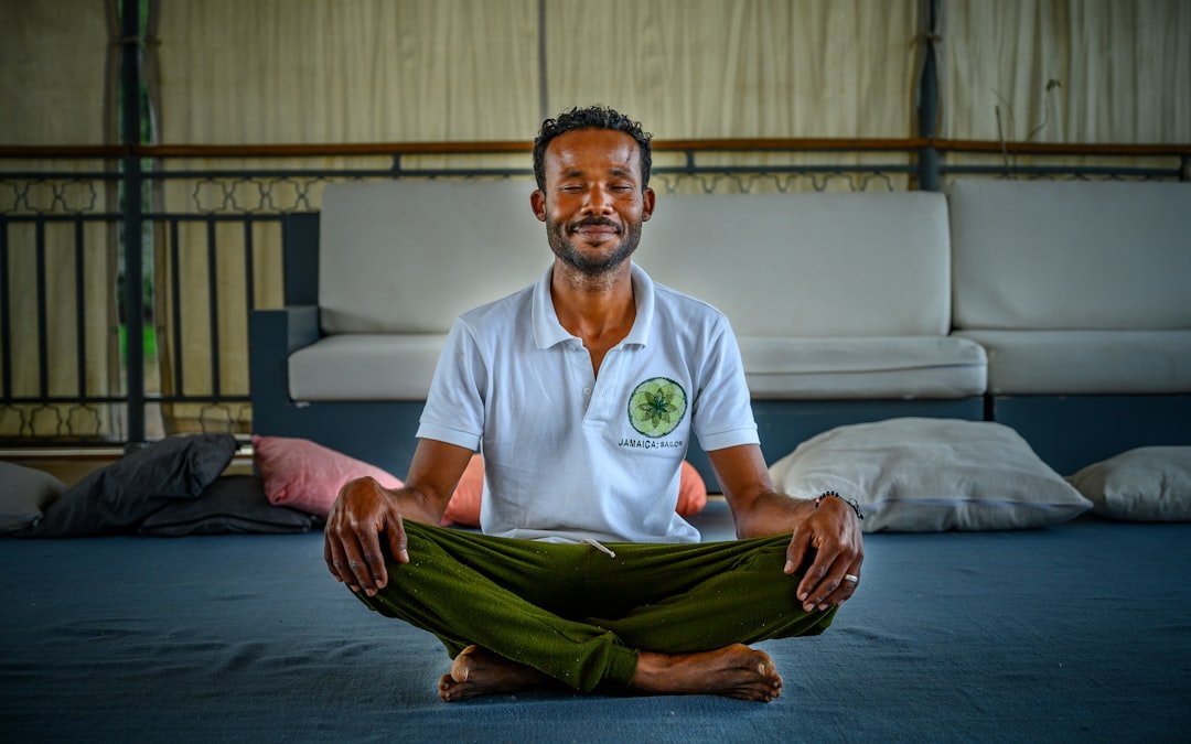 A man sitting in a lotus position on a bed