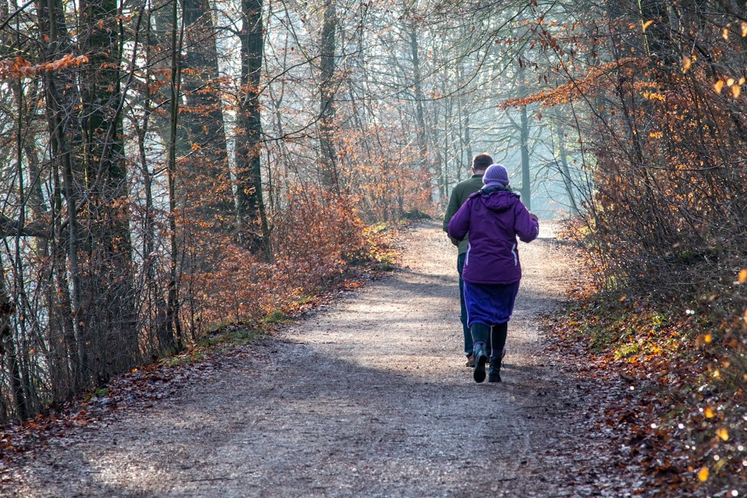 a woman walking down a dirt road in the woods